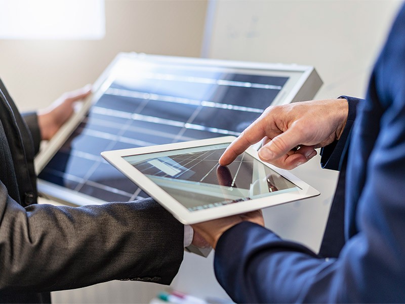 Close-up of two businessmen in office with solar cell and tablet