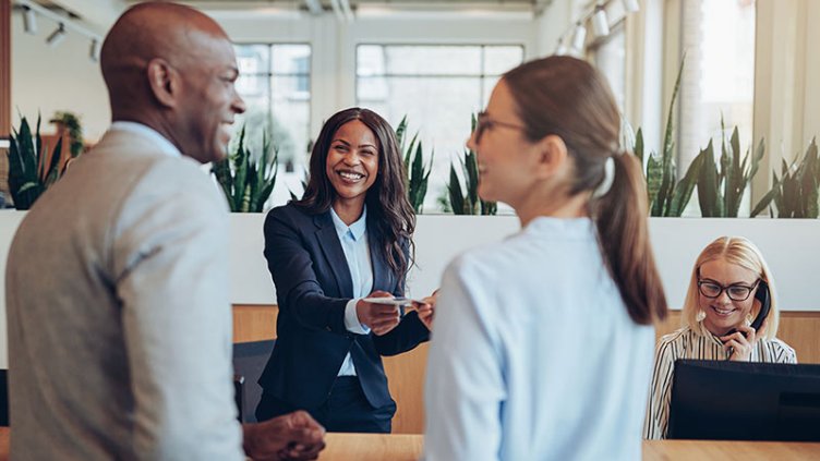 Smiling concierge helping two guests check in to a hotel