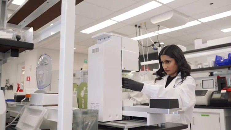 Lab technicians working through window with Manifold Bio logo 