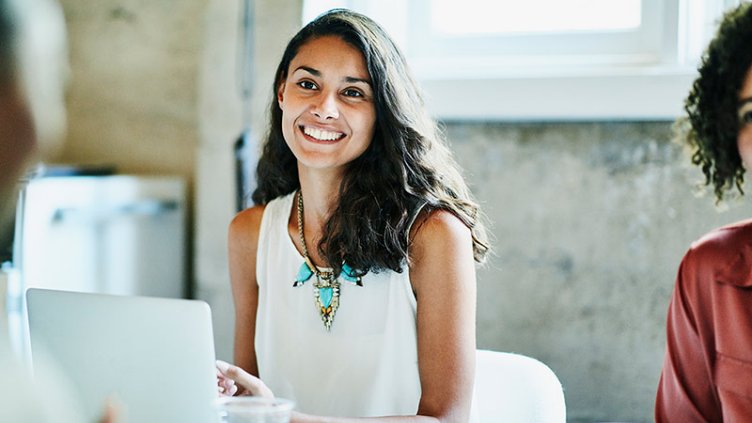 Smiling businesswoman in discussion with colleagues during meeting in office conference room