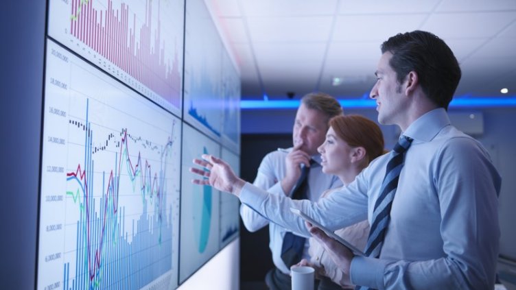 3 people(2 male and 1 female) looking at screen board and talking about data innovation