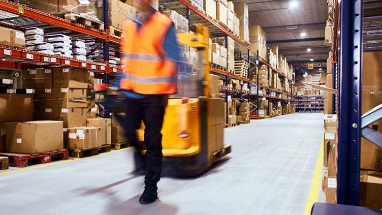 Warehouse worker operating loading container inside warehouse.