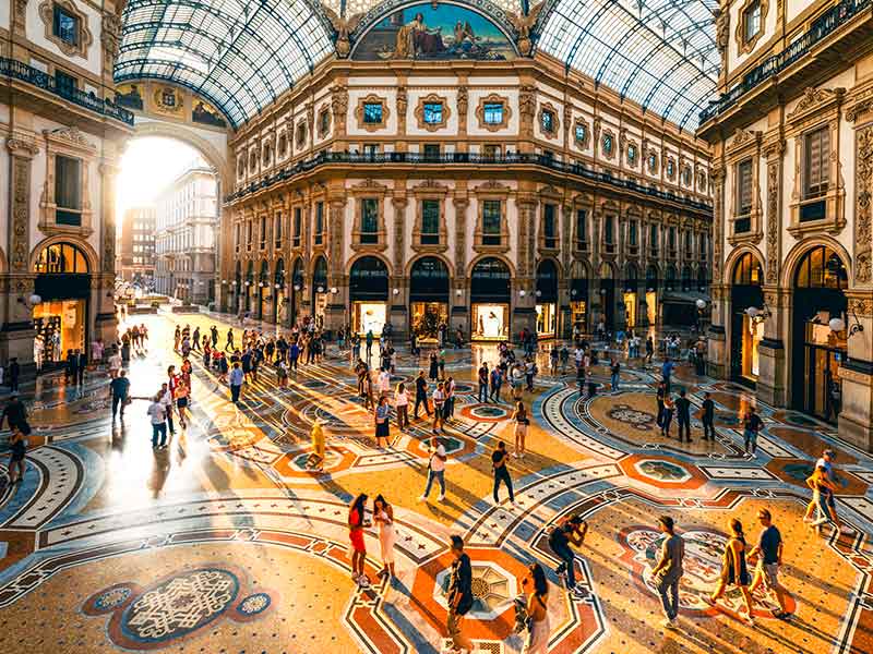 People in a luxury shopping mall in Milan at sunset.